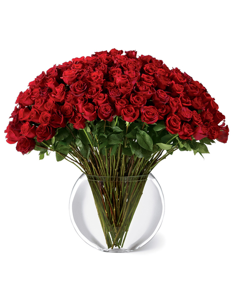 100 long-stemmed red roses in a clear glass vase
